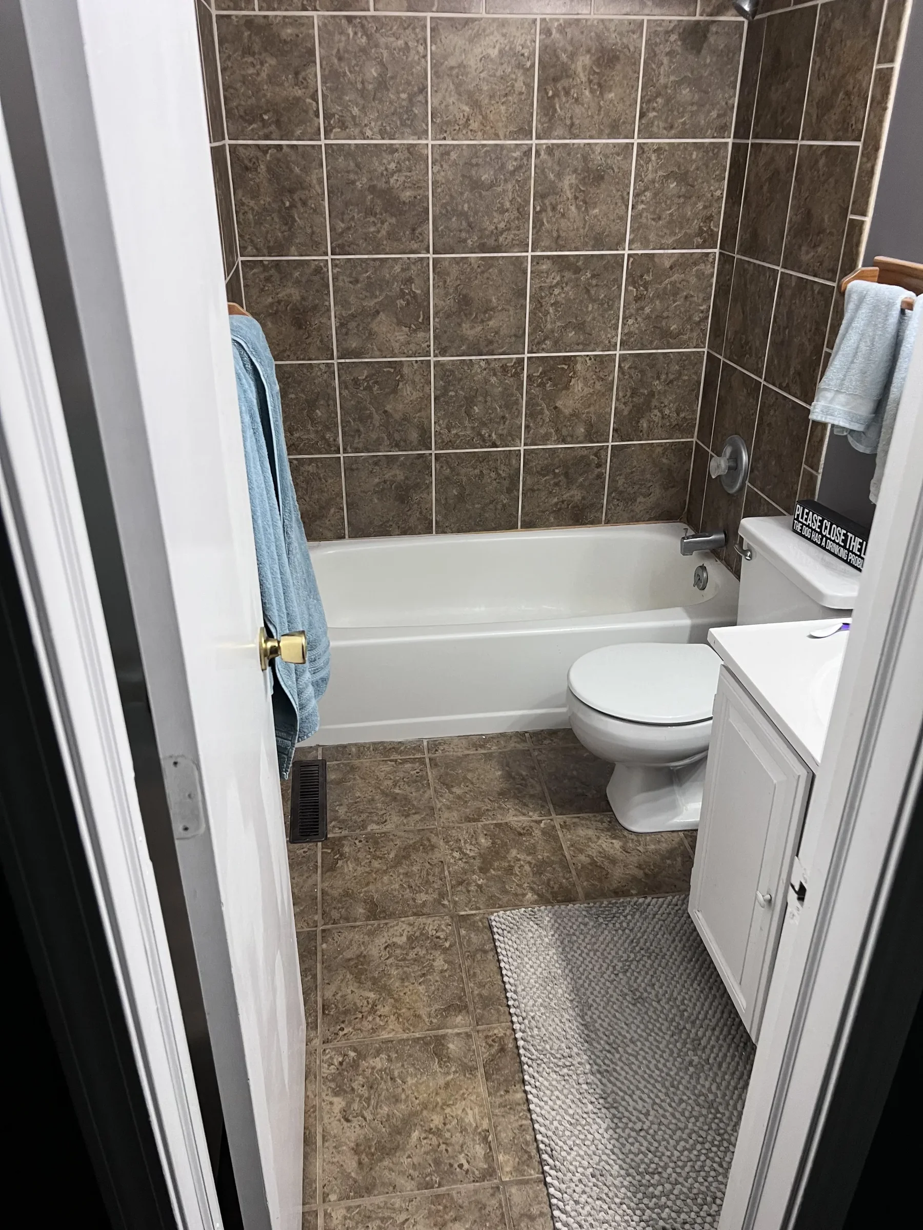 Dated bathroom before remodel with brown tile tub surround and beige floor tile