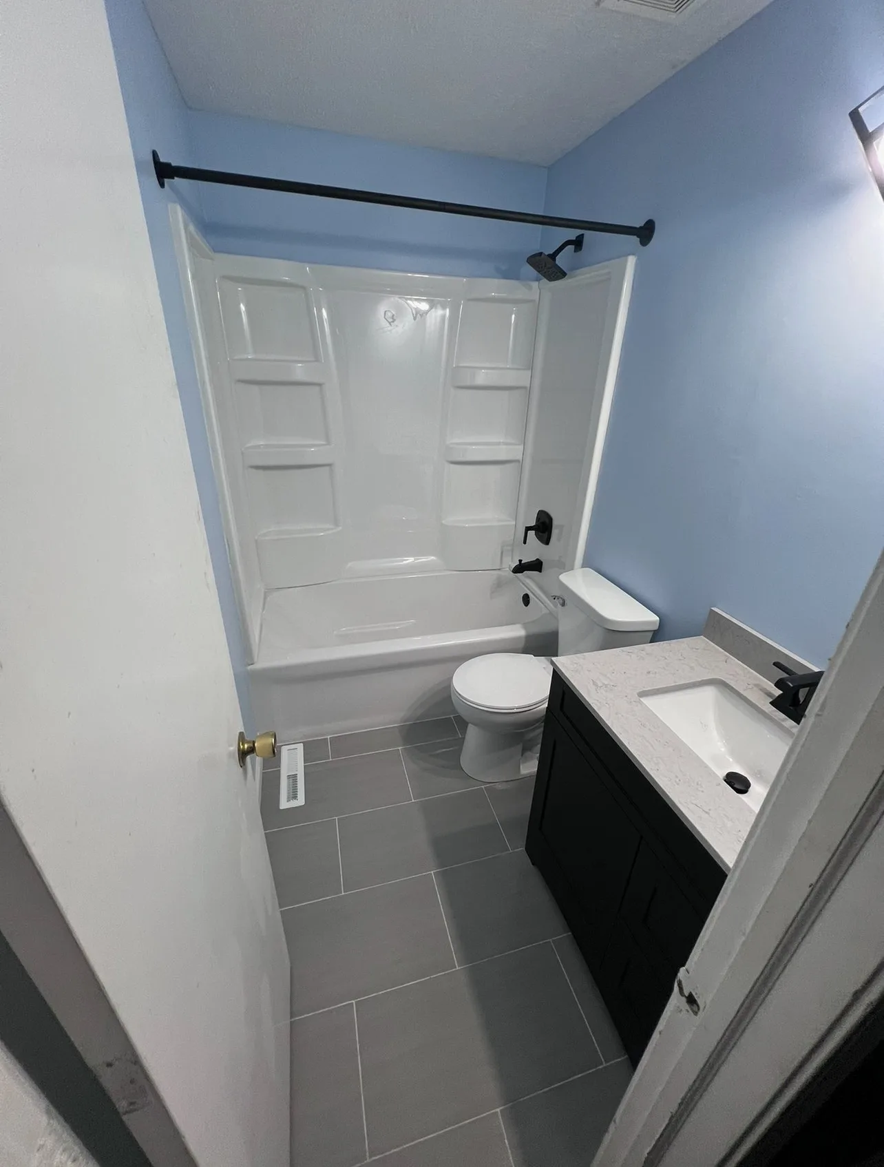 Finished bathroom with tub and shower surround, tile floor and dark vanity
