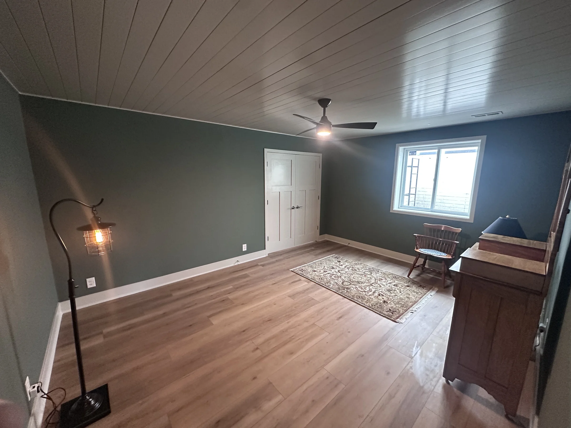 Finished room with shiplap ceiling, painted walls, custom trim, closet doors and new flooring