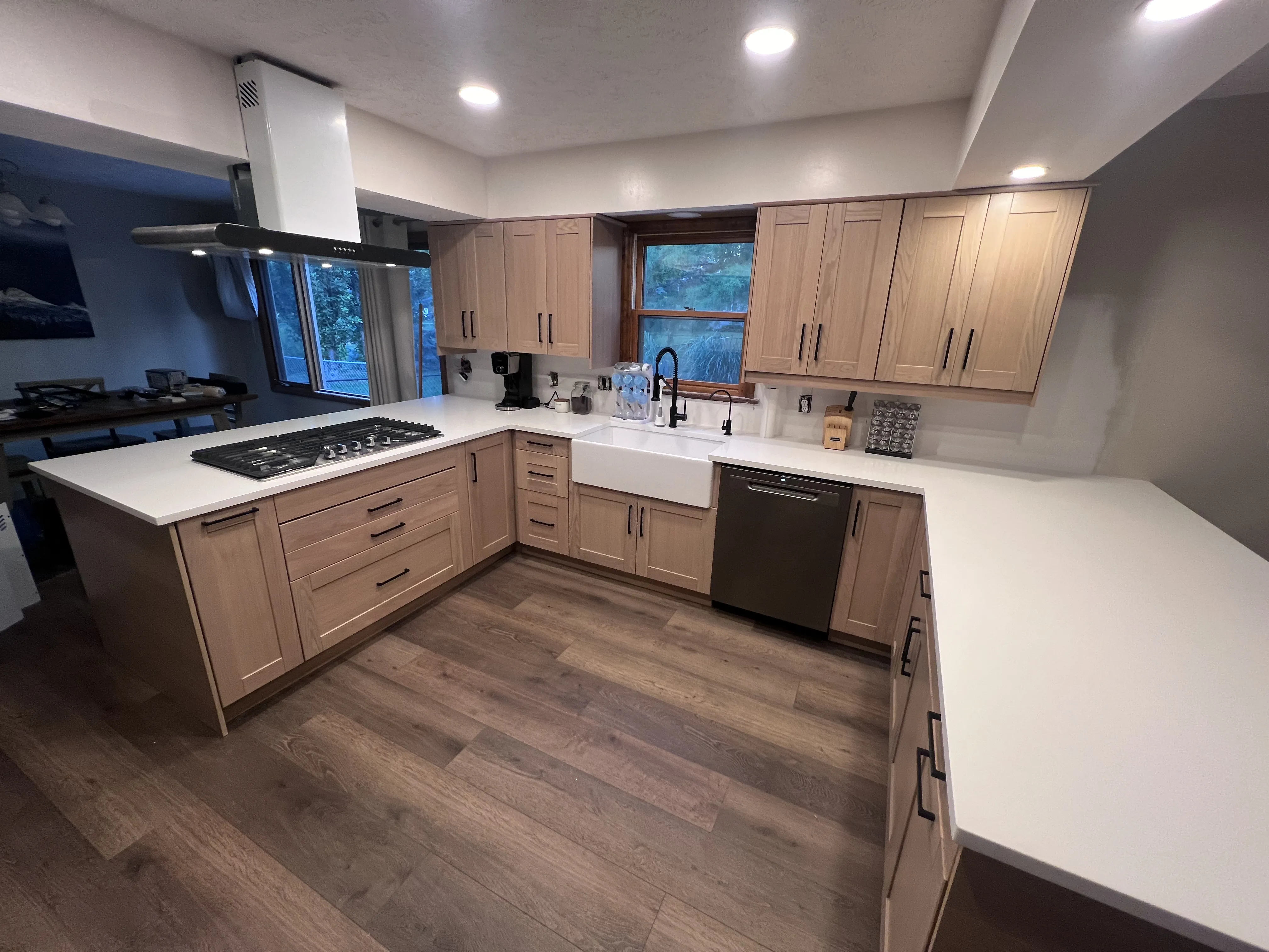 Finished kitchen remodel with light wood cabinets, white quartz counters and a farmhouse sink