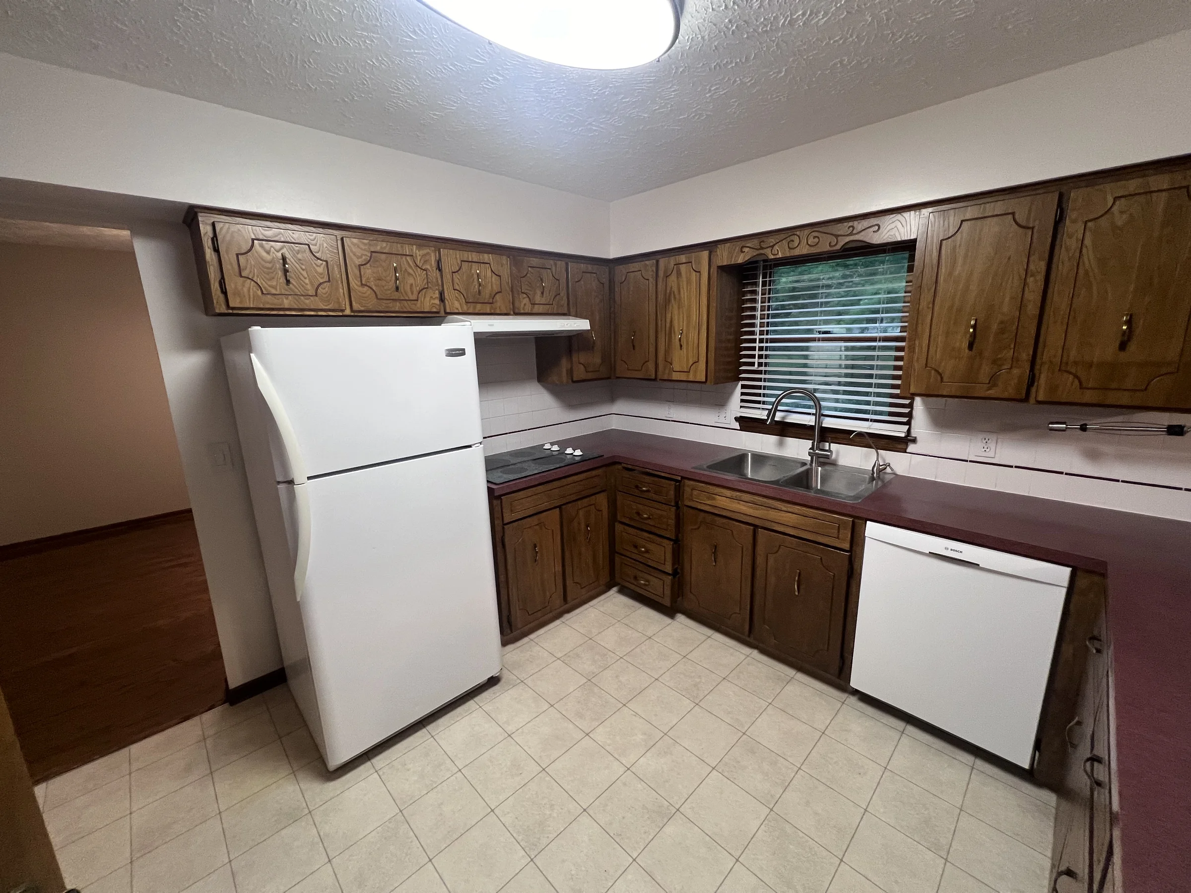 Original dated kitchen with dark oak cabinets and maroon laminate counters, before remodel