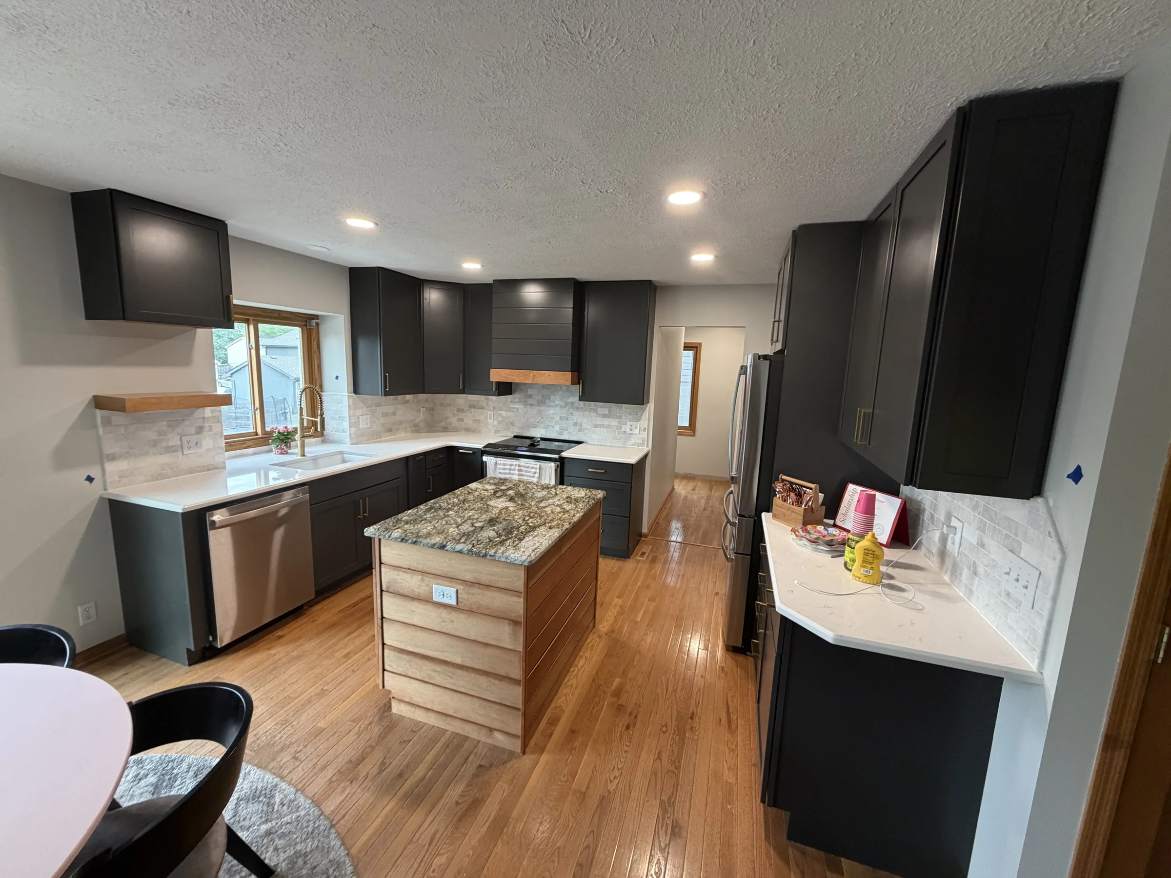 Modern kitchen remodel with dark shaker cabinets, quartz counters, tile backsplash and a wood-wrapped island