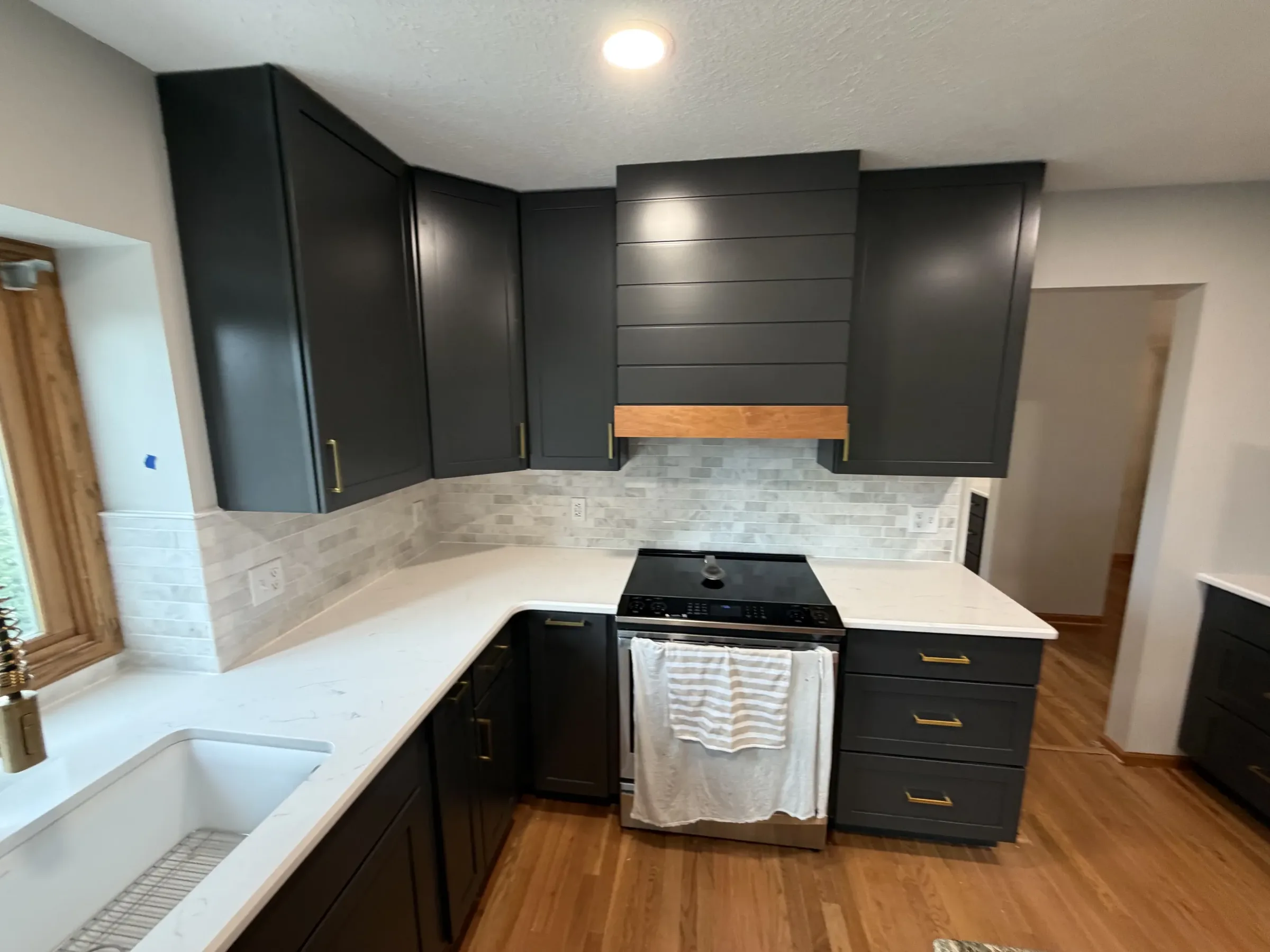 Dark shaker cabinets with marble tile backsplash and wood range hood surround