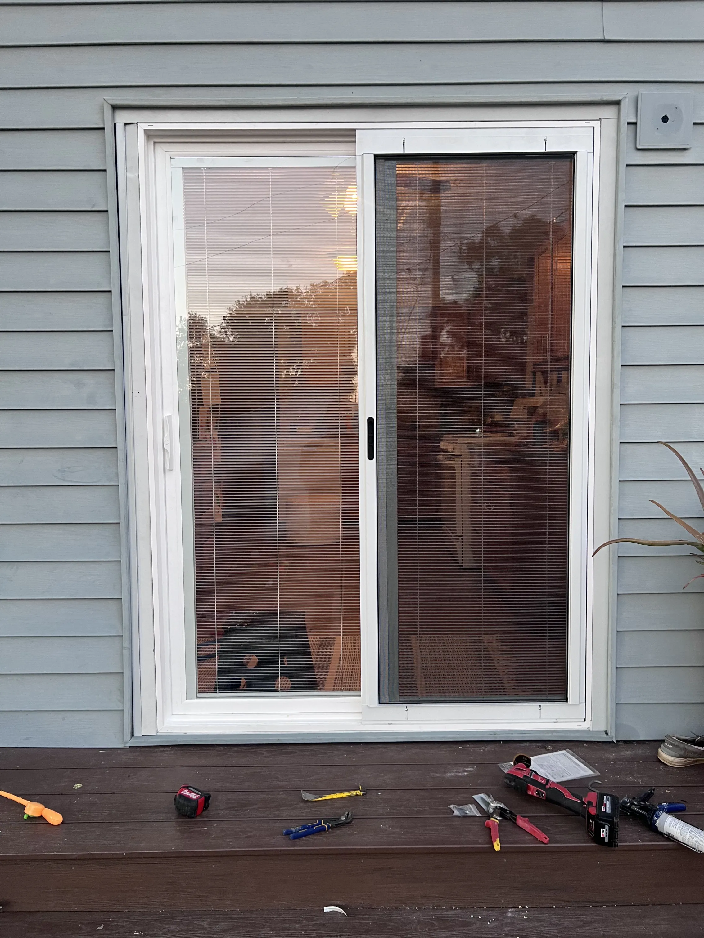 New white sliding patio door with built-in blinds installed in lap siding
